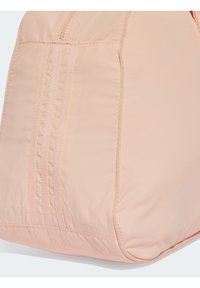 Meruňková látková taška s hladkou texturou, zdobená šitými liniemi a zipem nahoře. Zaoblené dno a měkké okraje.