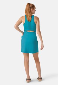 Un vestito sportivo color teal con design senza maniche, colletto alto e apertura sulla schiena. Presenta un corpetto aderente e una gonna svasata con tasche.