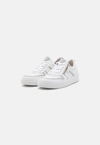 Baskets en cuir blanc avec une texture lisse, dotées d'une fermeture éclair sur le côté, d'accents argentés et d'un design de laçage classique. Semelle en caoutchouc.