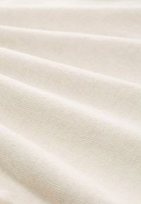 Crème-kleurige stof met een gestructureerd oppervlak, waarvan de horizontale plooien en de gladde afwerking aangeven dat het een zacht, geweven materiaal is.