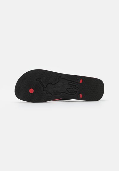 Black shoe sole with a textured pattern, featuring a red circular accent and a raised silhouette design in the center.