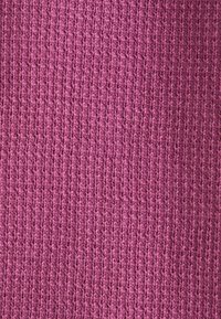 Tessuto a maglia di un ricco colore magenta, caratterizzato da un pattern testurizzato a coste e una finitura liscia, ideale per capi d'abbigliamento o accessori.