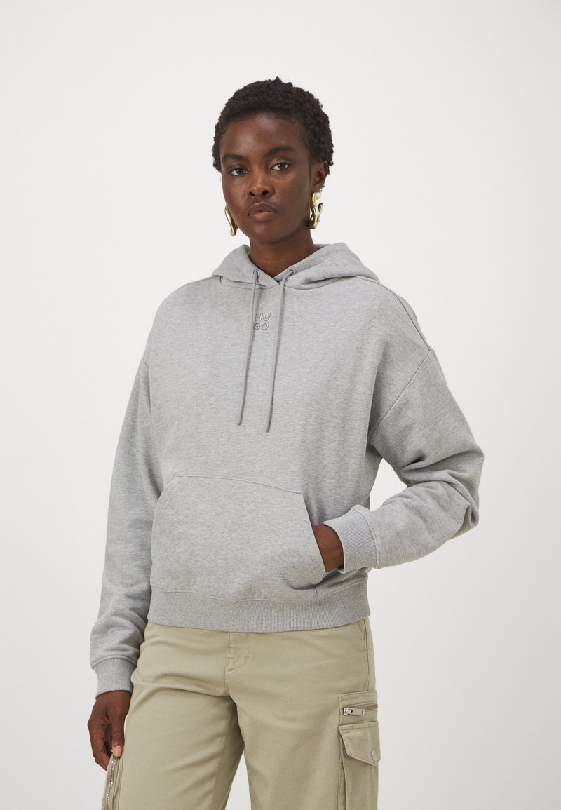 Felpa grigia realizzata in materiale morbido, con tasca a marsupio, cappuccio regolabile e polsini a costine. Abbinata a pantaloni cargo beige.