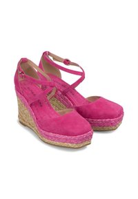 Chaussures à talons compensés en daim rose avec des brides croisées autour de la cheville et une plateforme en jute tressé. Bout arrondi et texture lisse. Hauteur d'environ 10 centimètres.