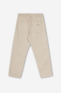 Pantalons en coton beige avec une taille élastique, deux poches arrières et une poche latérale supplémentaire. Présente des coutures visibles et une coupe décontractée.