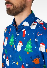 Camicia blu con bottoni caratterizzata da motivi festivi colorati, tra cui Babbo Natale, alberi di Natale, fiocchi di neve e bastoncini di zucchero.