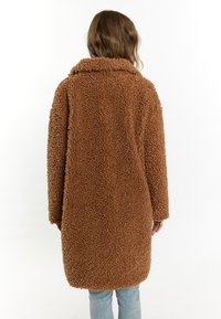 Brun, fuzzy, oversized frakke med krave og en blød, tekstureret finish. Designet har en lige form og lange ærmer.