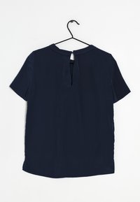 Blusa blu navy a maniche corte con apertura a chiave sul retro. Tessuto morbido e scollatura rotonda. Orlo leggermente curvato nella parte inferiore.
