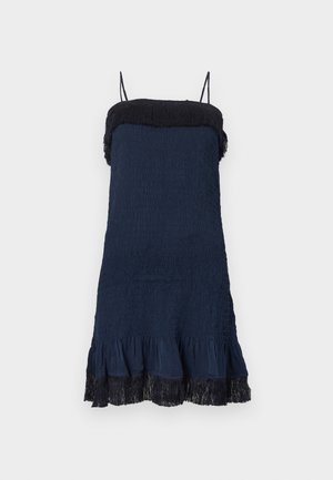 Rochie bleu închis din material texturat, cu tiv volanat și accent de franjuri negri la decolteu. Are bretele subțiri reglabile.