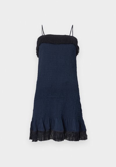 Tengerészkék ruha texturált anyagból, fodros szegéllyel és fekete rojtos díszítéssel a nyakkivágásnál. Vékony, állítható pántokkal rendelkezik.