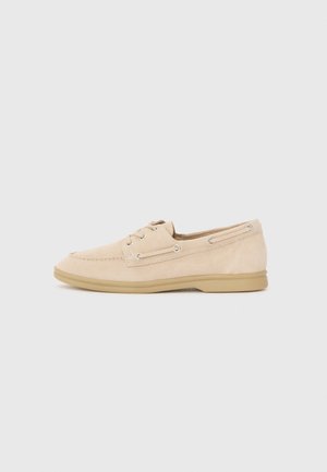 Beiger Wildleder-Casual-Schnürschuh mit Mokassinnaht und hellbrauner Gummisohle, seitlich auf neutralem Hintergrund gezeigt.
