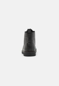Black leather ankle boots with a smooth texture, rounded toe, and a small pull tab at the back. Sturdy rubber sole.