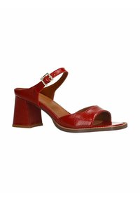 Rode gepatineerde leren sandalen met hak, open teen, enkelbandje en een vierkante blokhak. Bevat een gouden gesp-accent.