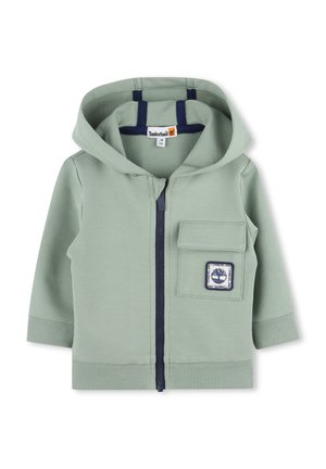 Haut à capuche zippé vert clair en coton doux, doté d'une poche avant avec un bord bleu marine et un patch logo. Manches et ourlet côtelés, design avec capuche.