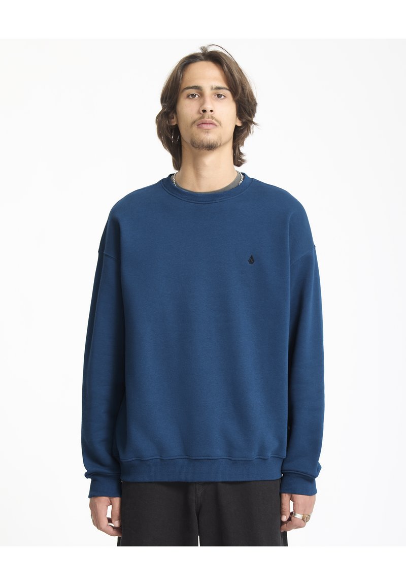 Blauwe sweatshirt in een relaxte pasvorm, gemaakt van zachte stof met een ronde hals. Bevat een klein zwart logo op de borst en geribbelde manchetten.