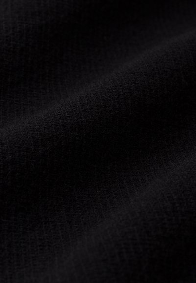 Tessuto nero con una superficie texture, caratterizzato da un morbido motivo intrecciato. Il materiale sembra spesso e accogliente, con delicate variazioni di lucentezza.