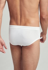 Mutande di cotone bianche con una texture liscia, caratterizzate da un design semplice e un elastico morbido con un discreto marchio sul retro.