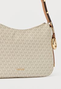 Beige olkalaukku, jossa kaikkialla toistuva MK-logokuvio, kultaiset metalliosat ja ruskea teksturoitu hihna, vetoketjukiinnitys ja kohokuvioitu merkin nimi.