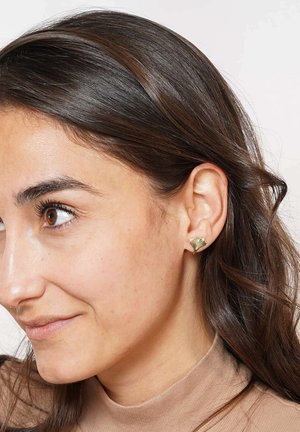 Gold-tone earrings shaped like fan leaves, featuring textured detailing and a polished finish. Worn on a model with dark hair.