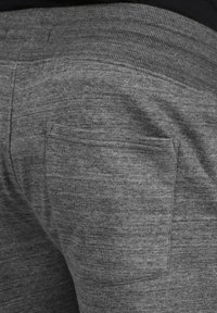 Pantalones de chándal grises hechos de una suave tela texturizada con una cintura acanalada y un pequeño detalle de un bolsillo en la parte posterior.