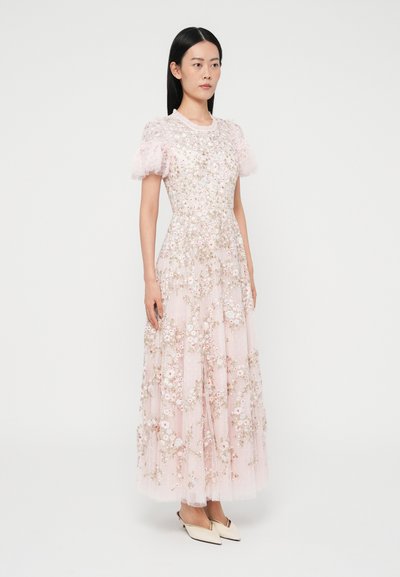 Lang lyserød kjole med blomsterbroderi, korte pufærmer i tyl, rund halsudskæring og delikate detaljer; båret med cremefarvede hæle.