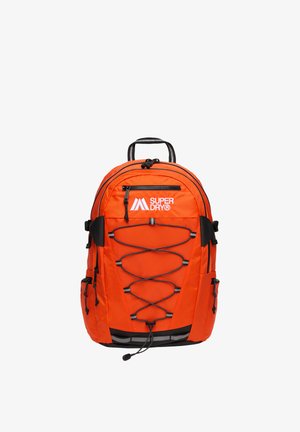 Jaskrawo pomarańczowy plecak z czarnymi elastycznymi linkami krzyżującymi się z przodu, zapinanymi na zamek kieszeniami i białym logo „Superdry” na środku górnej części.