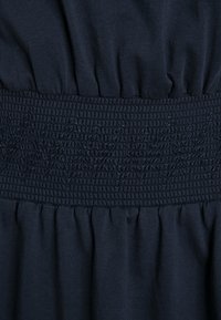 Granatowy materiał o marszczonej strukturze; marszczony środek ma podniesiony, geometryczny wzór, zapewniający elastyczność i formowanie.