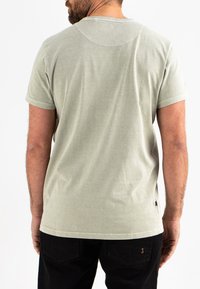 Lichtgroene katoenen t-shirt met een ronde hals, korte mouwen en een zachte textuur. Heeft zichtbare stiksels en een klein logo-detail aan de onderkant.