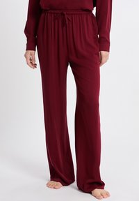 Bordeaux wijd-gesneden broek van zacht materiaal, met een elastische tailleband met drawstring en zijnaad voor een ontspannen pasvorm.