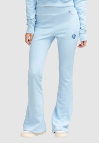 Pantalons de jogging évasés bleus en tissu doux, avec un motif cousu, un logo discret et une taille ajustée avec des poches.