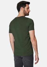 Krótki rękaw, oliwkowa koszulka wykonana z miękkiej bawełny. Posiada okrągły dekolt i prosty brzeg, z gładką i jednolitą fakturą.