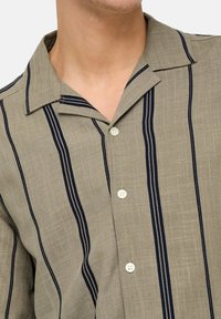 Light gray short-sleeve shirt with navy vertical stripes, button-down collar, and two button closures, made from textured linen fabric.