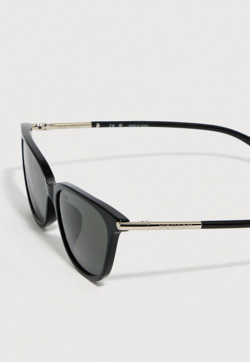 Black rectangular sunglasses with dark lenses and thin gold arms resting on a white surface.