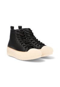 Un par de zapatillas altas negras con suelas de goma beige gruesas y punteras redondas beige, con cordones negros y lengüetas en la parte posterior.