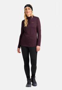 Maroon long-sleeve top with a half-zip and logo, paired with black leggings featuring panel accents, and sturdy black hiking shoes.