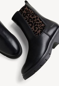 Černé kožené kotníkové boty s texturovanou hnědou leopardí potiskovou elastickou boční částí a robustní podrážkou pro lepší trakci.