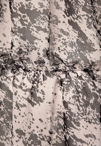 Różowa tkanina z szarym abstrakcyjnym wzorem. Tekstura jest gładka, z marszczeniami wzdłuż szwu, które dodają głębi.