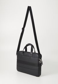 Black laptop bag with a textured leather finish, featuring dual handles and a detachable shoulder strap. Zip closure with logo accent.