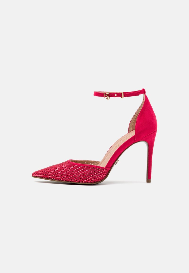 Chaussure à talon haut rouge avec bride à la cheville, bout pointu et strass décoratifs sur la partie avant de la chaussure.