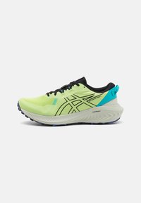 Scarpa sportiva gialla neon con accenti e lacci neri, caratterizzata da una tomaia texturizzata, un design elegante e una suola bianca imbottita con dettagli blu.