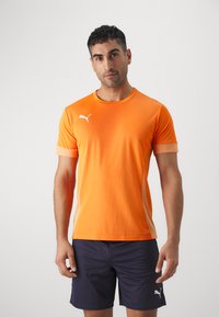 Oranž sportlik T-särk, mis on valmistatud hingavast kangast, valge Puma logo vasakul rinnal ning kontrastset värvi aktsendid varrukatel.