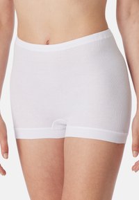 Mutandine bianche in cotone con una superficie liscia, vita elasticizzata e taglio a metà coscia. Presenta un piccolo aperture sul davanti.