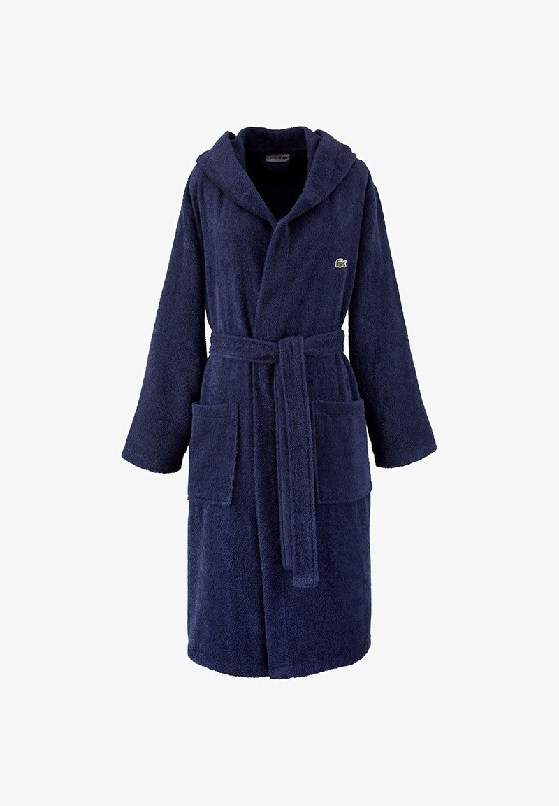 Accappatoio in spugna blu navy con cappuccio, due grandi tasche anteriori, cintura da annodare in vita e logo ricamato sul petto. Texture morbida.