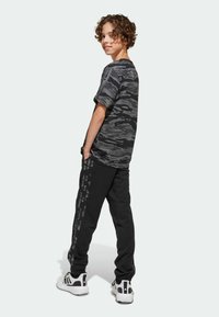 adidas Sportswear SEASONAL ESSENTIALS CAMOUFLAGE KIDS - Verryttelyhousut - black/multicolor