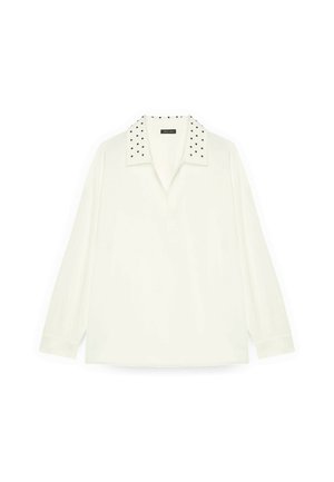 Camisa polo de manga larga blanca con cuello con tachuelas negras. Fabricada en tejido suave con un corte relajado, cuenta con una tapeta frontal y aberturas laterales.