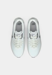 Ζευγάρι λευκών αθλητικών παπουτσιών Nike Air Max με κορδόνια, σε άνωθεν θέα σε απλό λευκό φόντο.