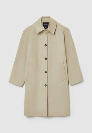 Cappotto beige con taglio dritto, colletto e maniche a tre quarti. Presenta bottoni neri e due tasche frontali. Tessuto dalla texture liscia.