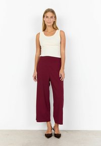 Kreemivärvi tank top ja burgundy laiad püksid. Sile kangas elastse vöökohtaga. Teravpruunid kontsad. Minimalistlik disain.