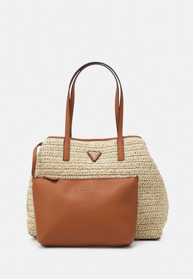 Sac cabas tissé beige avec de longues anses marron et une pochette avant marron zippée, tous deux ornés du logo de la marque Guess.