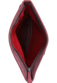 Hnědý kožený interiér kabelky s hladkým povrchem, zapínání na zip a kapsou na jedné straně. Vnitřní podšívka má kontrastní jasně červenou barvu.